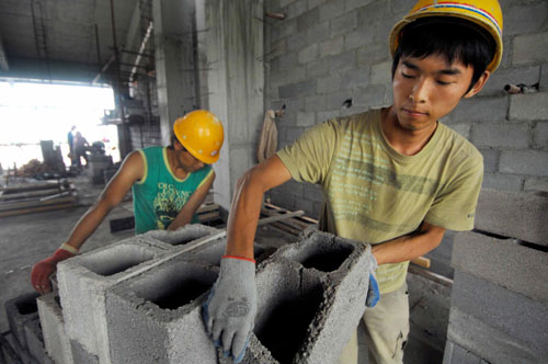 Students carry air bricks at North University of Nationalities in Yinchuan, Northwest China`s Ningxia Hui autonomous region, Aug 9, 2010. Wearing a safety helmet and work gloves, they wheeled sandstones and mixed cement and pebbles together during the hot, scorching days. The college students are using their summer vacation to work part-time at the university. I planned to go home at first, but I changed my mind when I learned that the school was recruiting workers for the construction of a new student hostel. I want to be financially independent, said Yang Xiping, from Inner Mongolia, who makes 75 yuan per day working from 6 am to 7 pm, with a two-hour nap at noon. About 60 students are spending their summer vacation at the construction site.